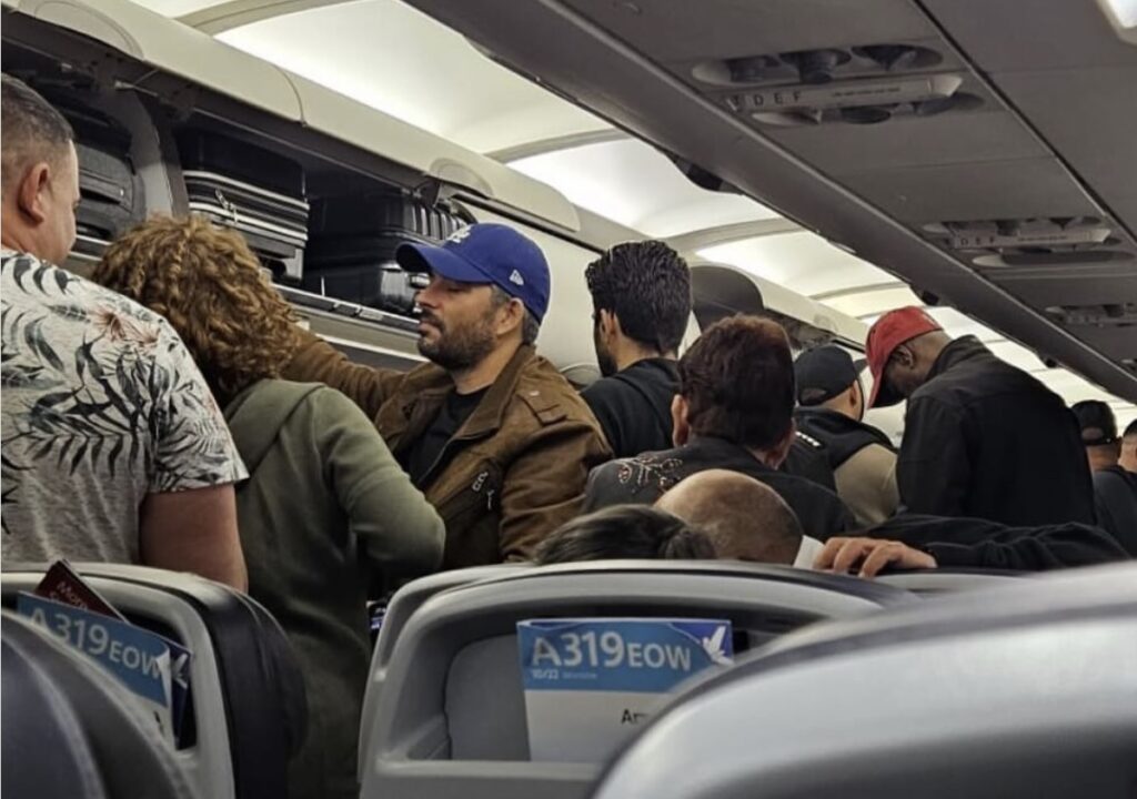 Pasajeros acomodando equipaje en compartimento de avión.